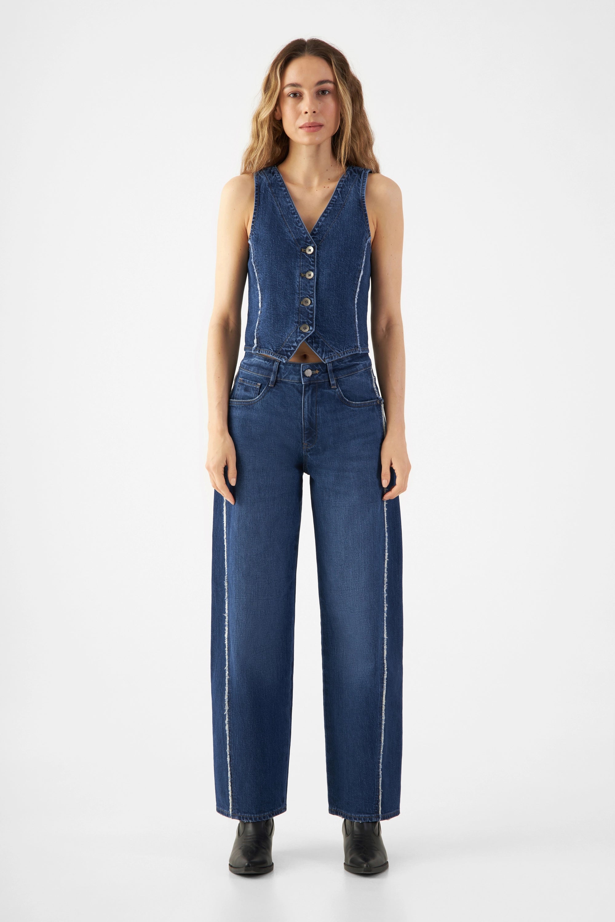 Taillierte dunkelblaue Denim-Weste mit V-Ausschnitt und Knopfleiste; Bio-Denim, minimaler Stretch, kurze Länge, Fray-Details an den Seiten.