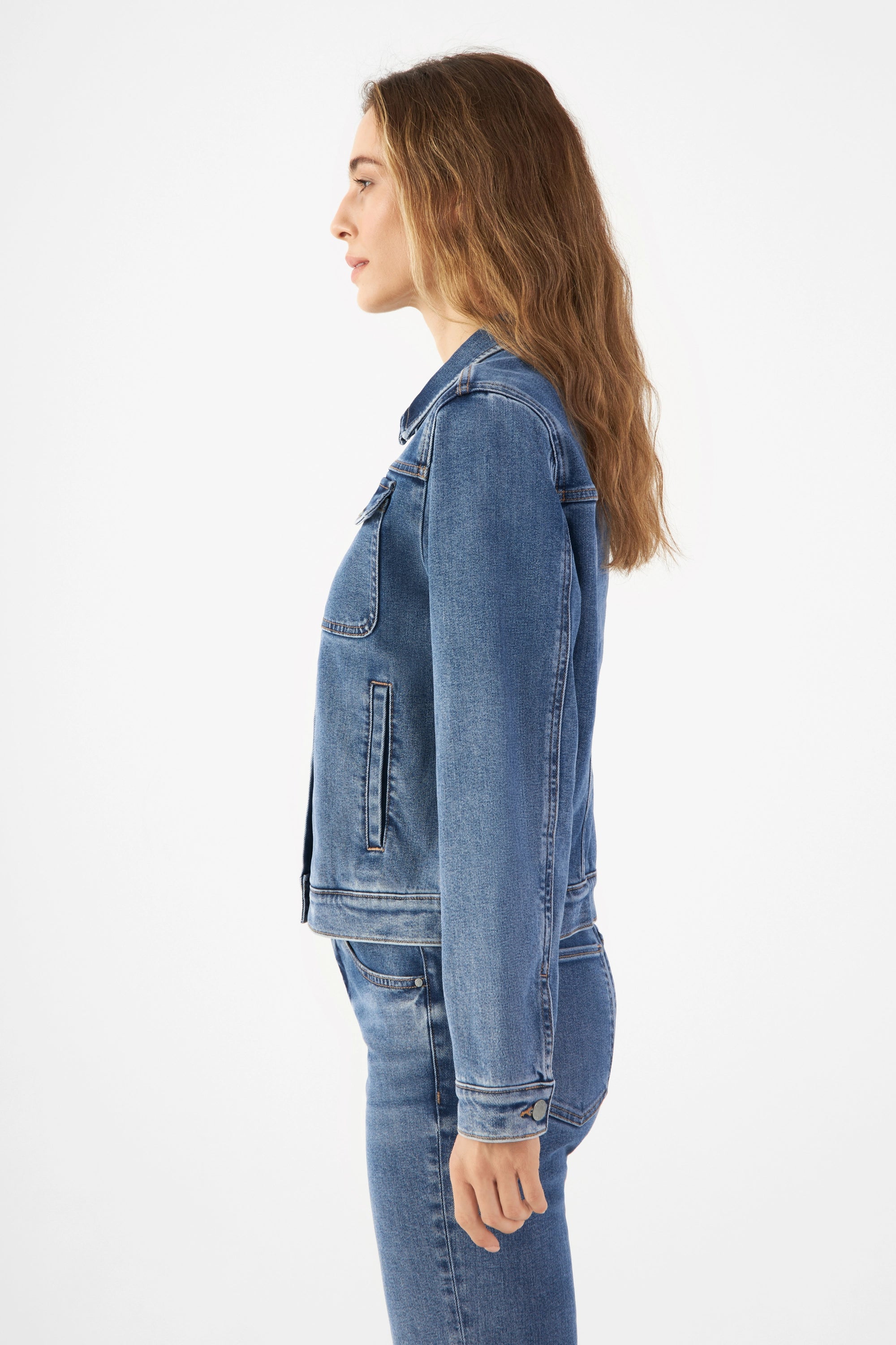 Seitenansicht einer Person in der blauen CALLISTO Jeansjacke (Medium Blue) mit Brusttaschen und geradem Schnitt.