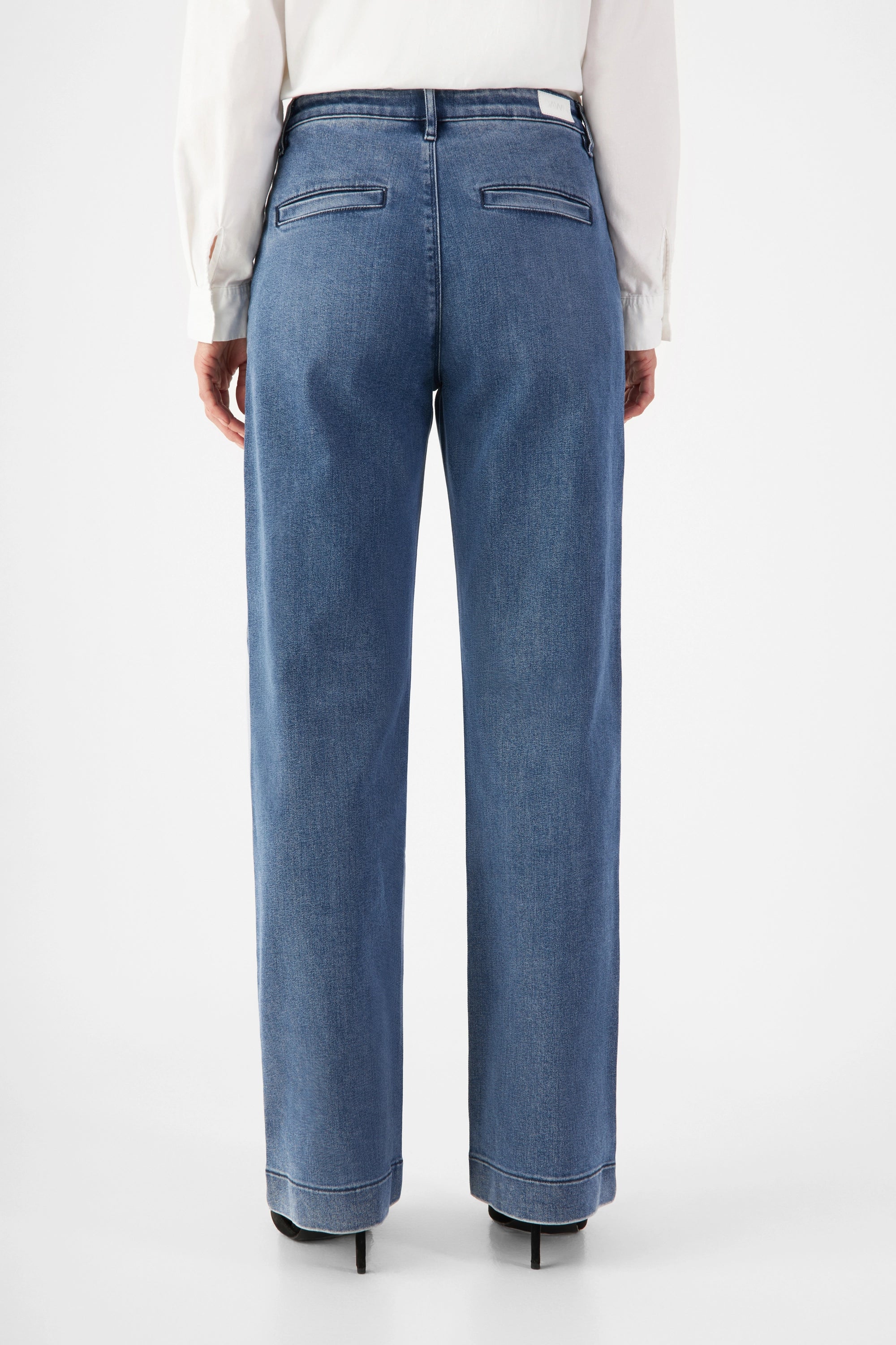 Rückenansicht der GLOW Flared Soft Tencel Denim-Chino in Medium Blue: mittelhohe Taille, weiteres Bein, hintere Paspeltaschen.