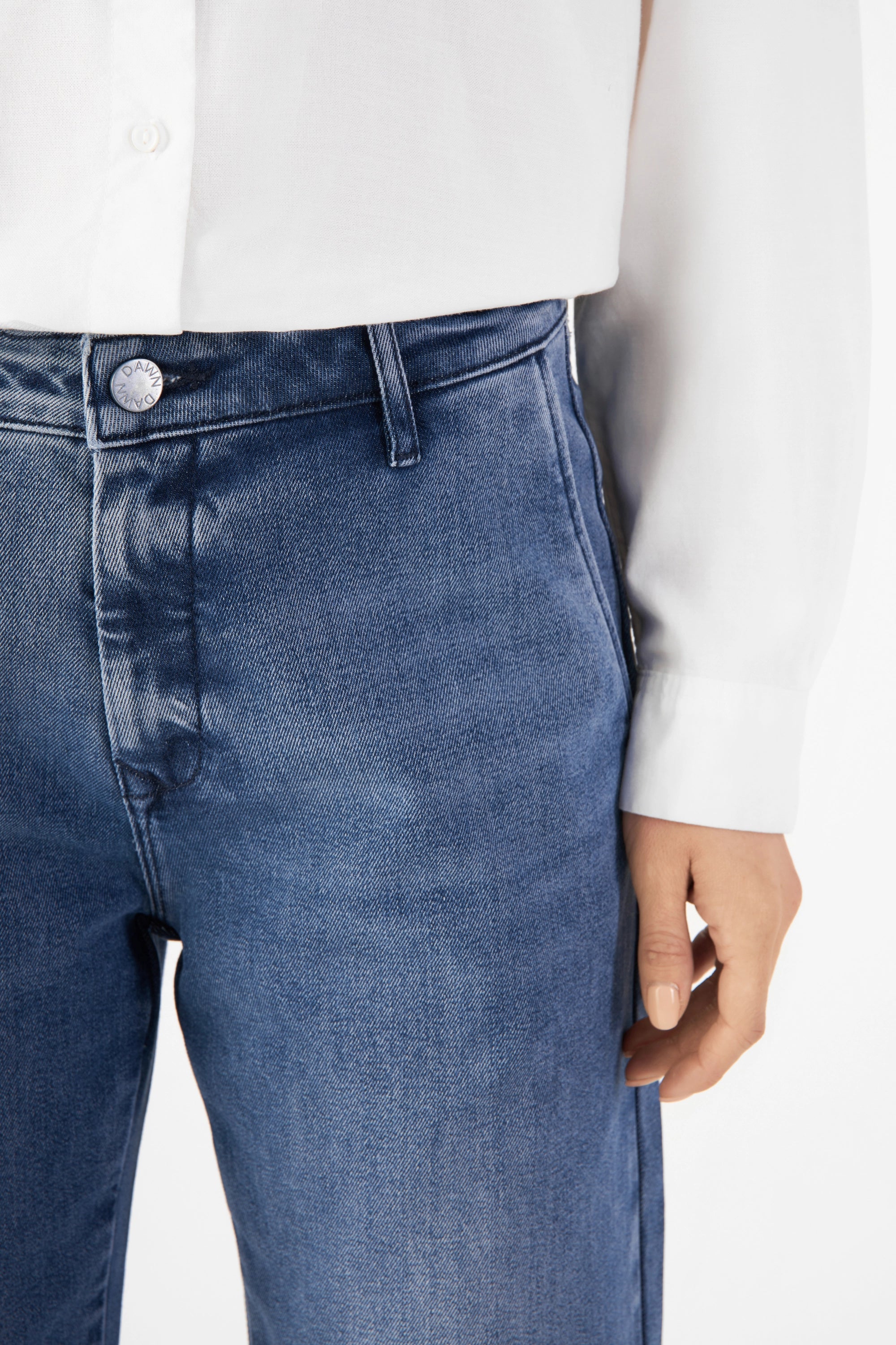 GLOW Flared Soft Tencel Denim-Chino in Medium Blue, mittlere Taille, ausgestelltes Bein; DAWN-Bundknopf sichtbar.