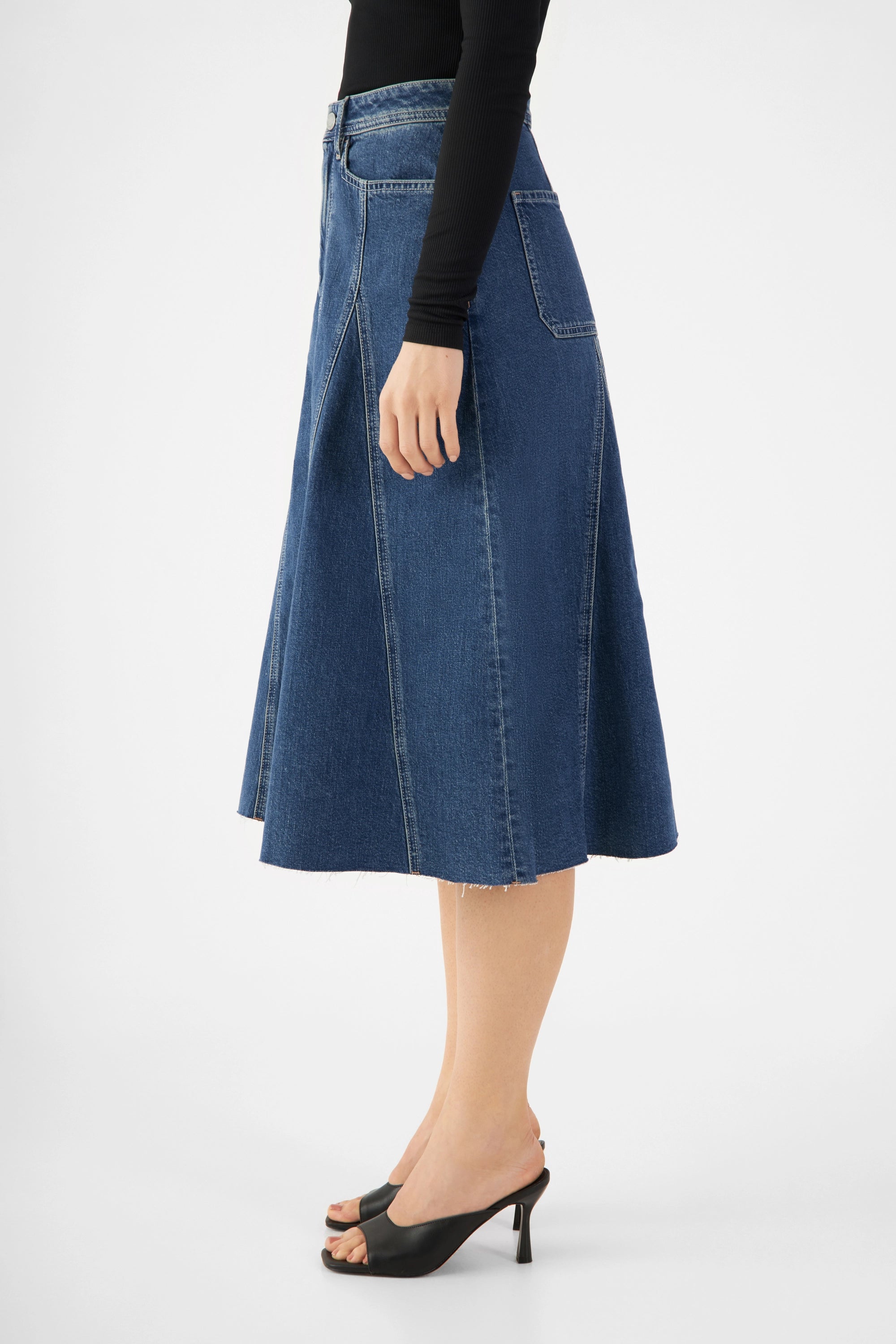 Seitenansicht des SOL Denim-Midirocks Vintage Blue mit mittelhohem Bund, ausgestelltem Schnitt und offener, leicht fransiger Saum; sichtbare Panel-Nahtdetails.