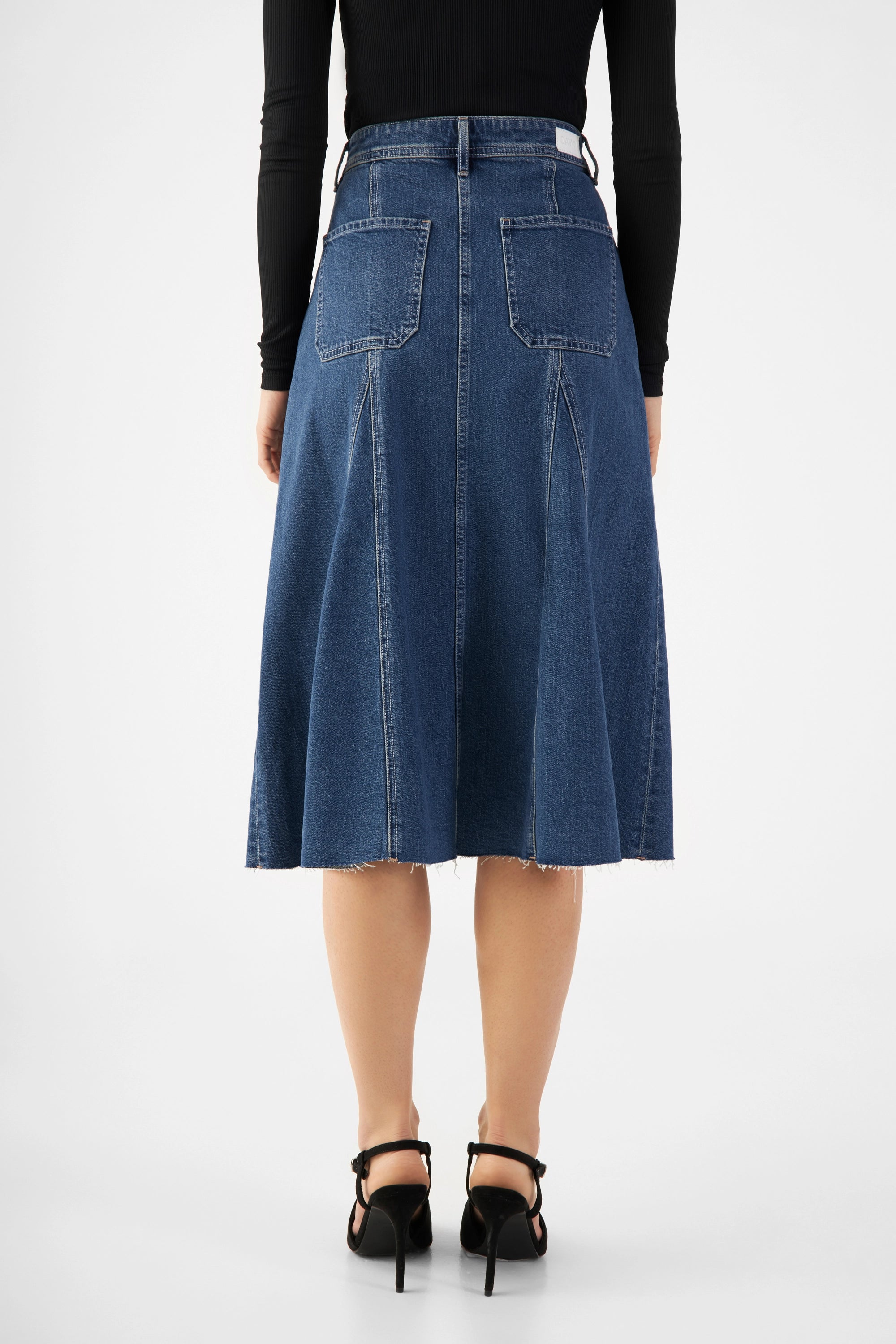 Rückansicht des Vintage-Blue SOL Midirocks: mittelhoher Bund, ausgestellter Schnitt, offener Saum mit Fransen; Taschen.