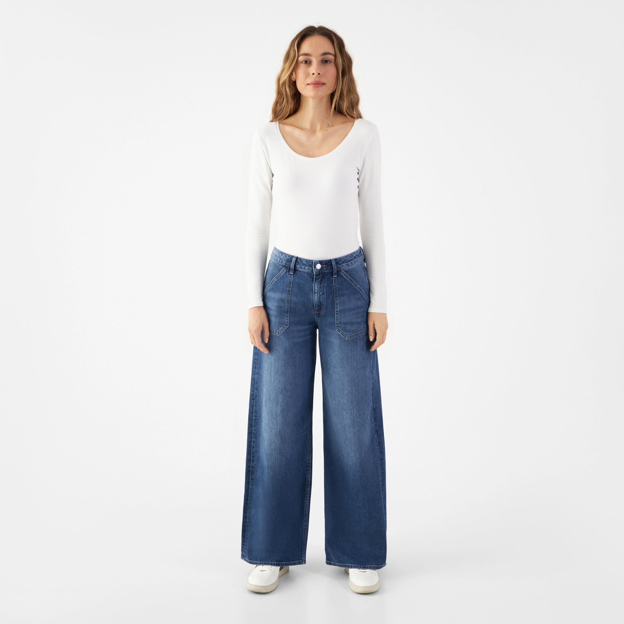 SUNNY Worker Jeans in Medium Blue: mit weitem, geradem Bein; Fronttaschen im Worker-Stil; Modell trägt weißes Langarmshirt.