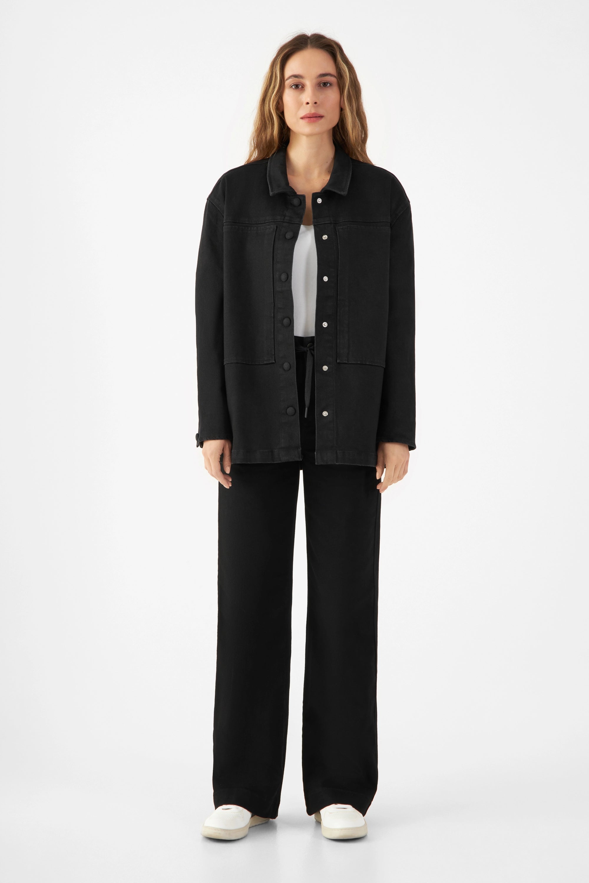 Schwarze QUIET Jacke aus TENCEL-Denim, lockerer kastiger Schnitt, Fronttaschen, Druckknöpfe; Model trägt sie über Top.